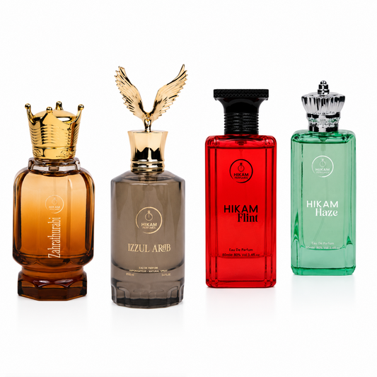 Four men's cologne bottles from Hikam and Zahir perfume displayed side-by-side on a white background. The bottles include Zahir (amber liquid with a gold crown cap), Izzul Arab (gray-brown liquid with a gold eagle cap), Hikam Flint (red liquid with a black cap), and Hikam Haze (green liquid with a silver cap).